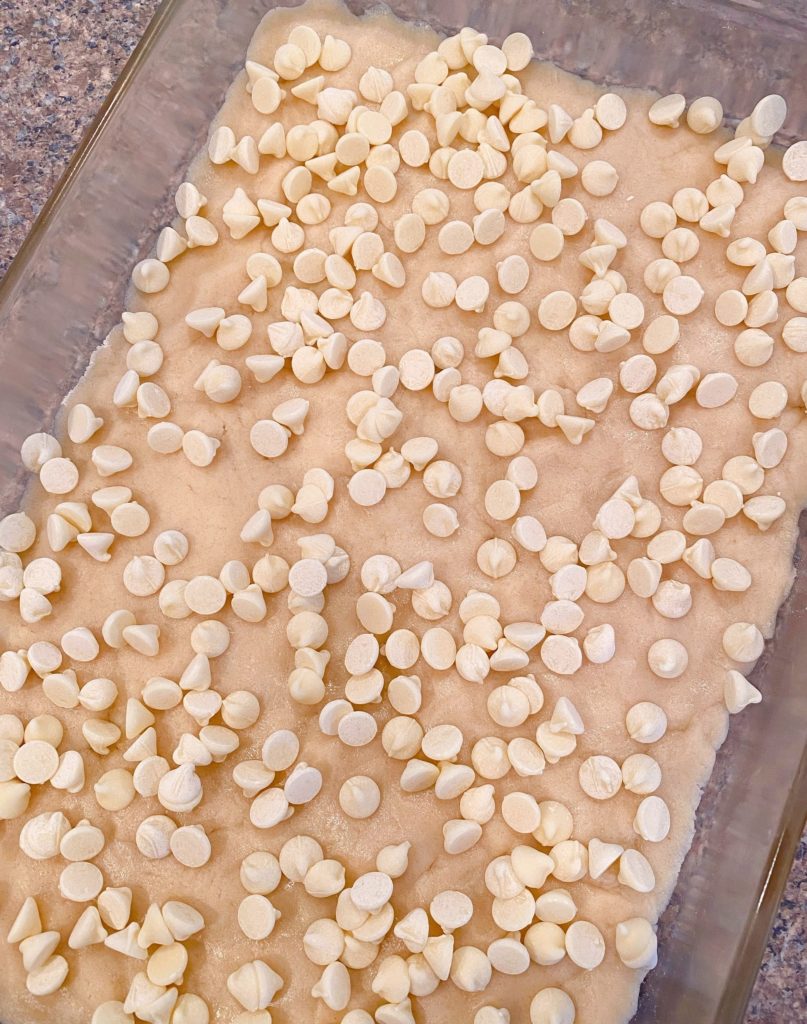 Cookie dough pressed into bottom of 13 x 9 inch pan sprinkled with white chocolate chips.n 