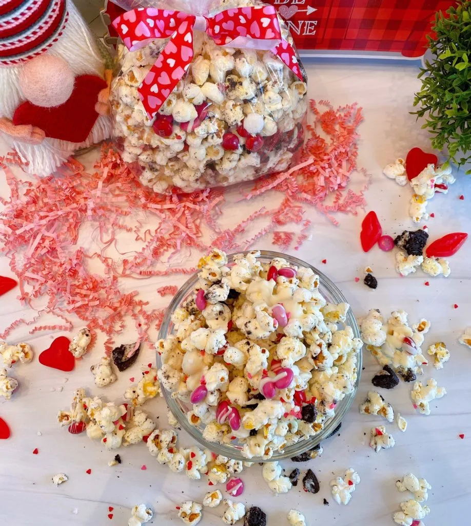 Bowl full of Cookies and Cream Popcorn and a bag filled with it and tied with a Valentines Ribbon.