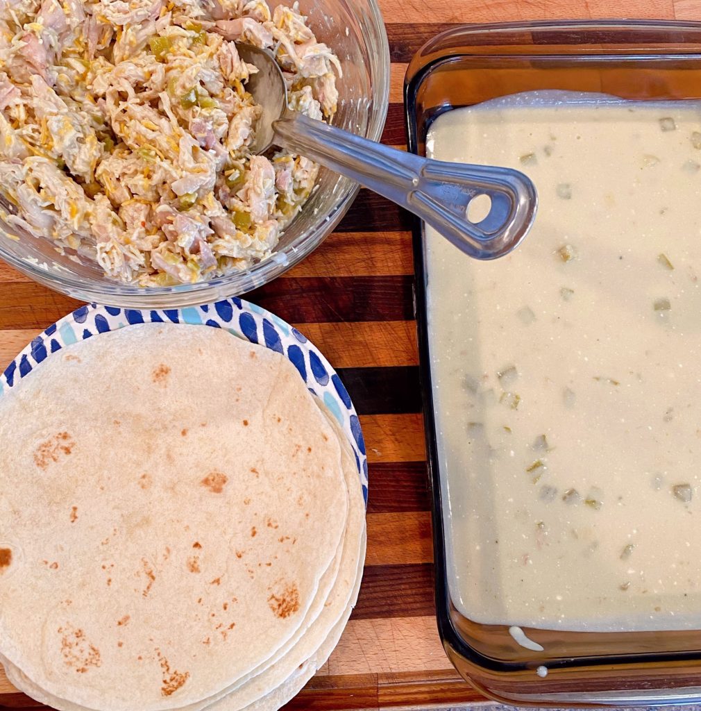 All the ingredients ready on a counter to create the enchiladas. The chicken filling, tortillas, and baking pan.