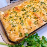 9 x 13 Casserole dish full of Creamy Chicken Flour Enchiladas surrounded by cilantro.