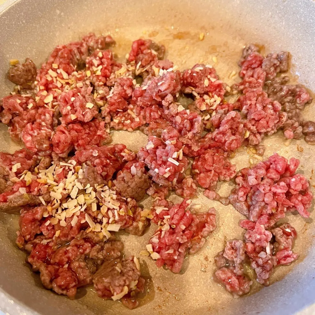 Large skillet with ground beef and dried onions over medium high heat.