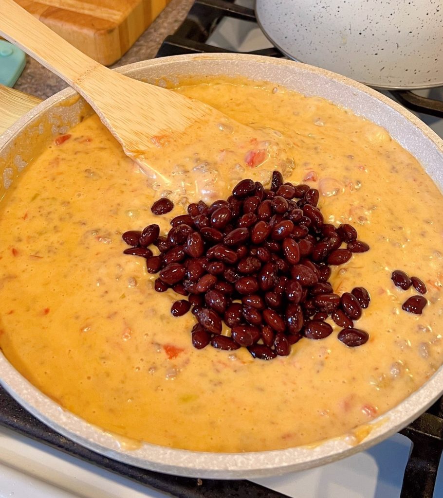 Adding Black Beans to the hot queso dip.