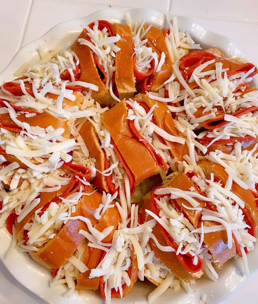 Cheese stuffed into each slider in a white baking dish.