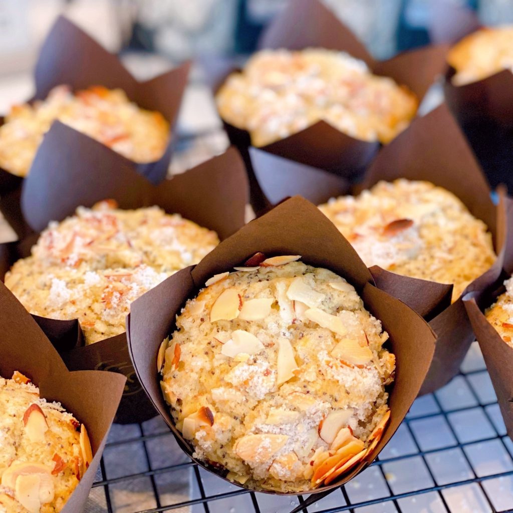 Bakery Style Almond Poppy Seed Muffins on a cooling rack in brown baking papers.