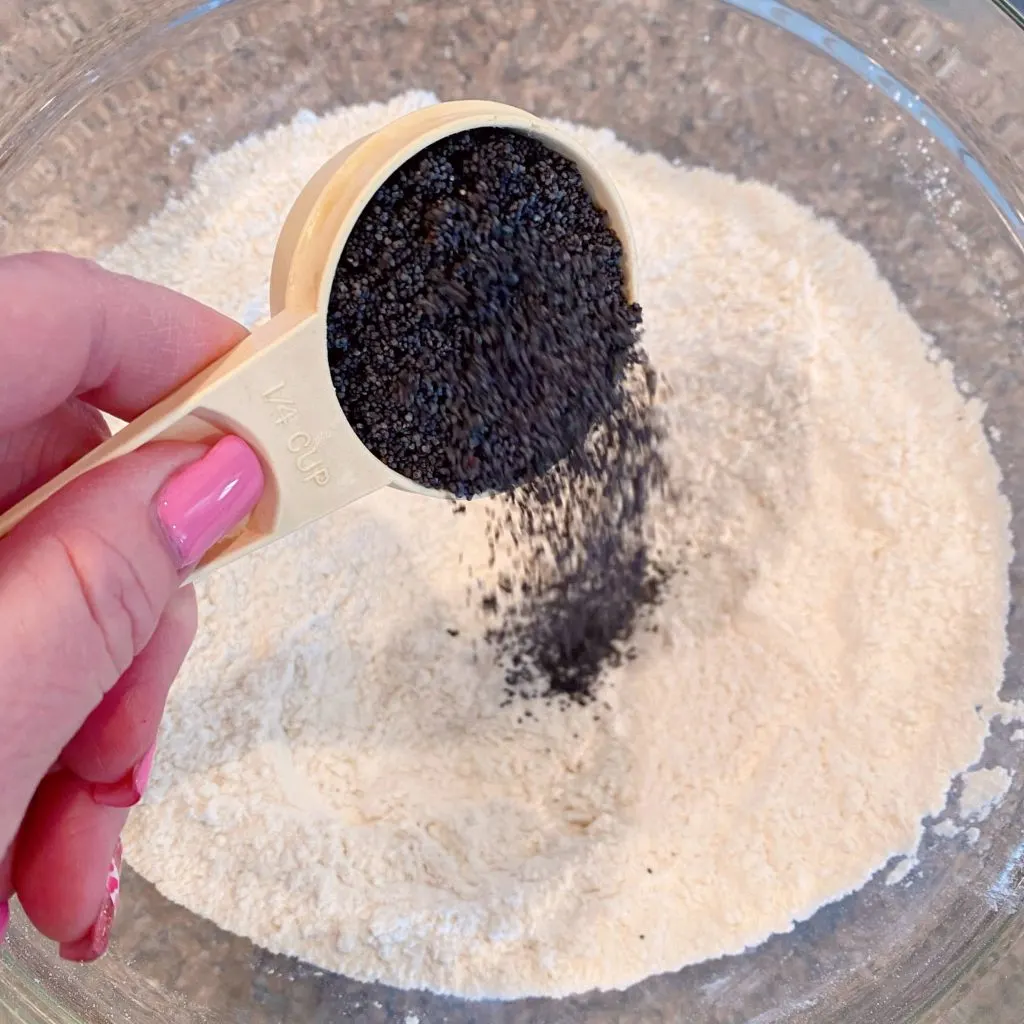 Adding poppy seeds to dry ingredients.