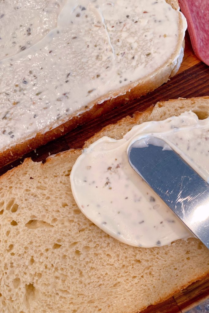 Spreading Herbed mayo on sour dough bread.