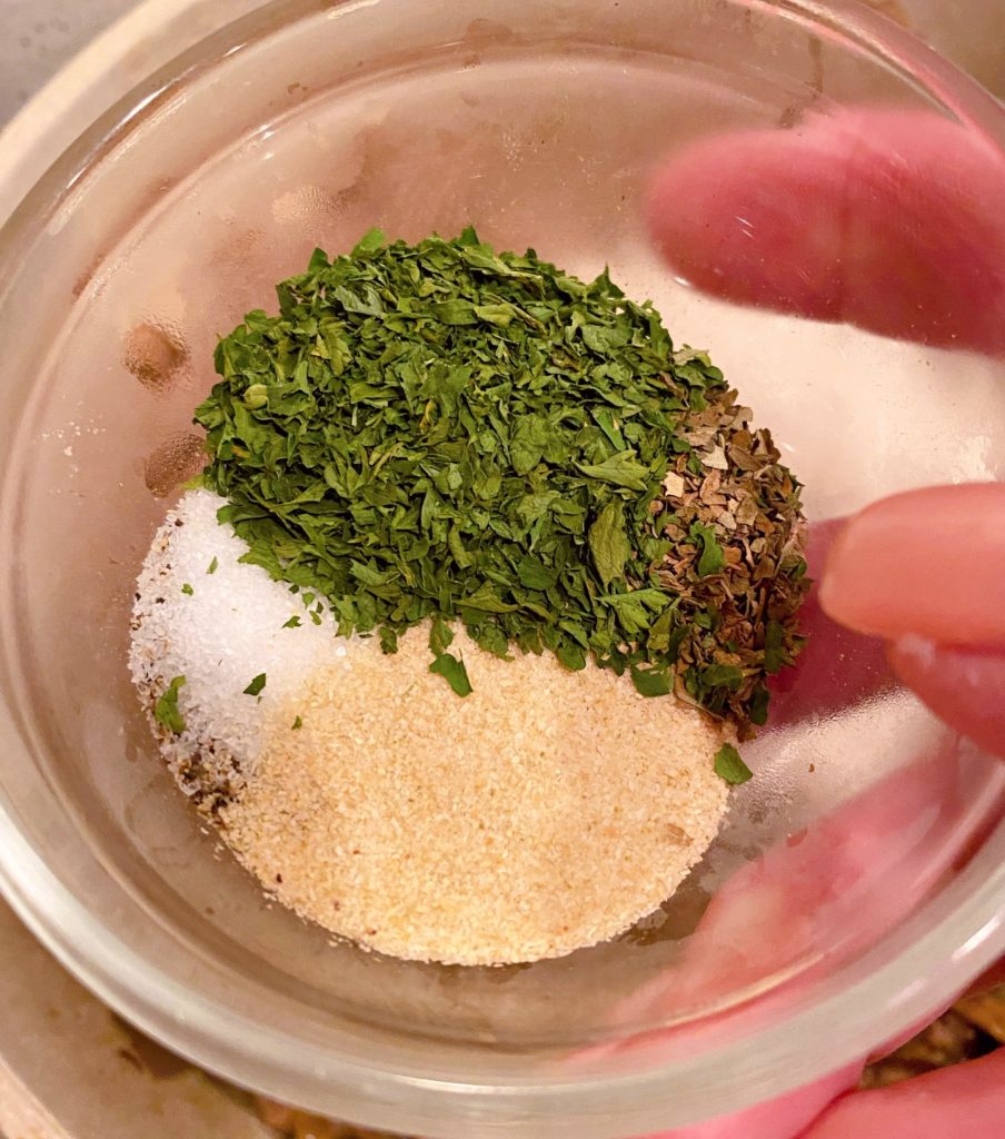 Seasoning in a small bowl being added to stroganoff mixture.
