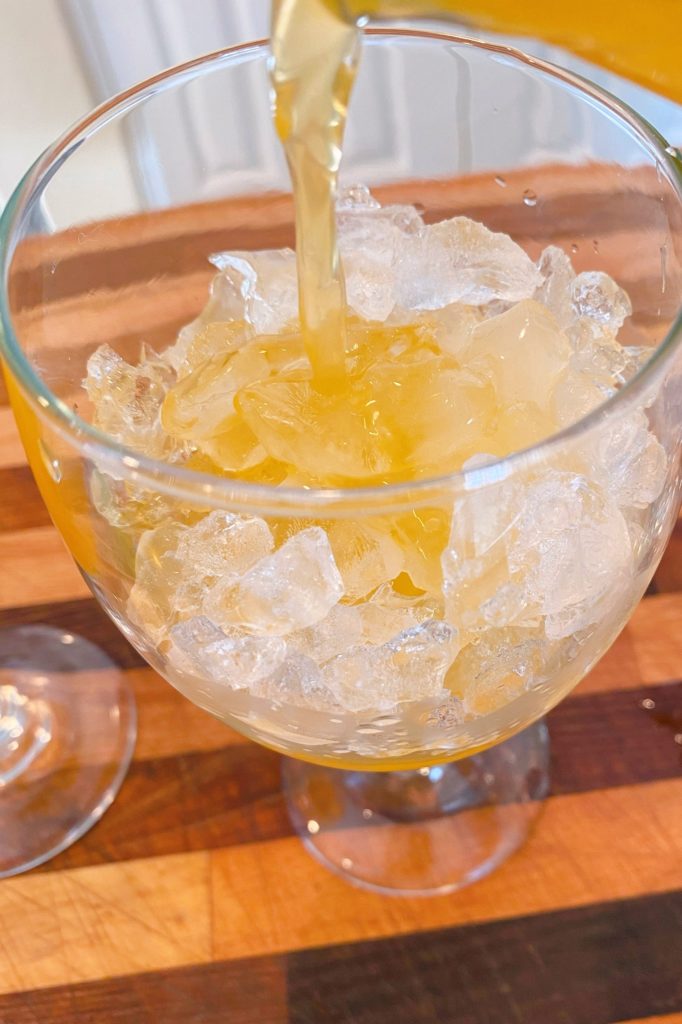 Goblet with ice adding passion fruit.
