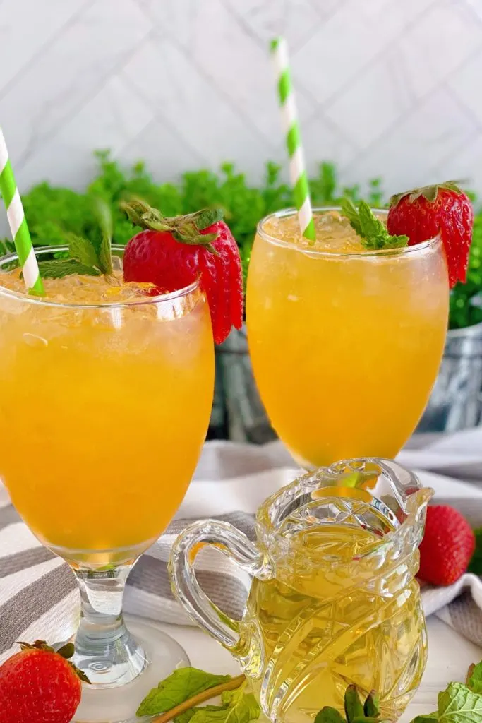 Non-alcoholic Passion Fruit Julep in two glasses with sliced strawberries.