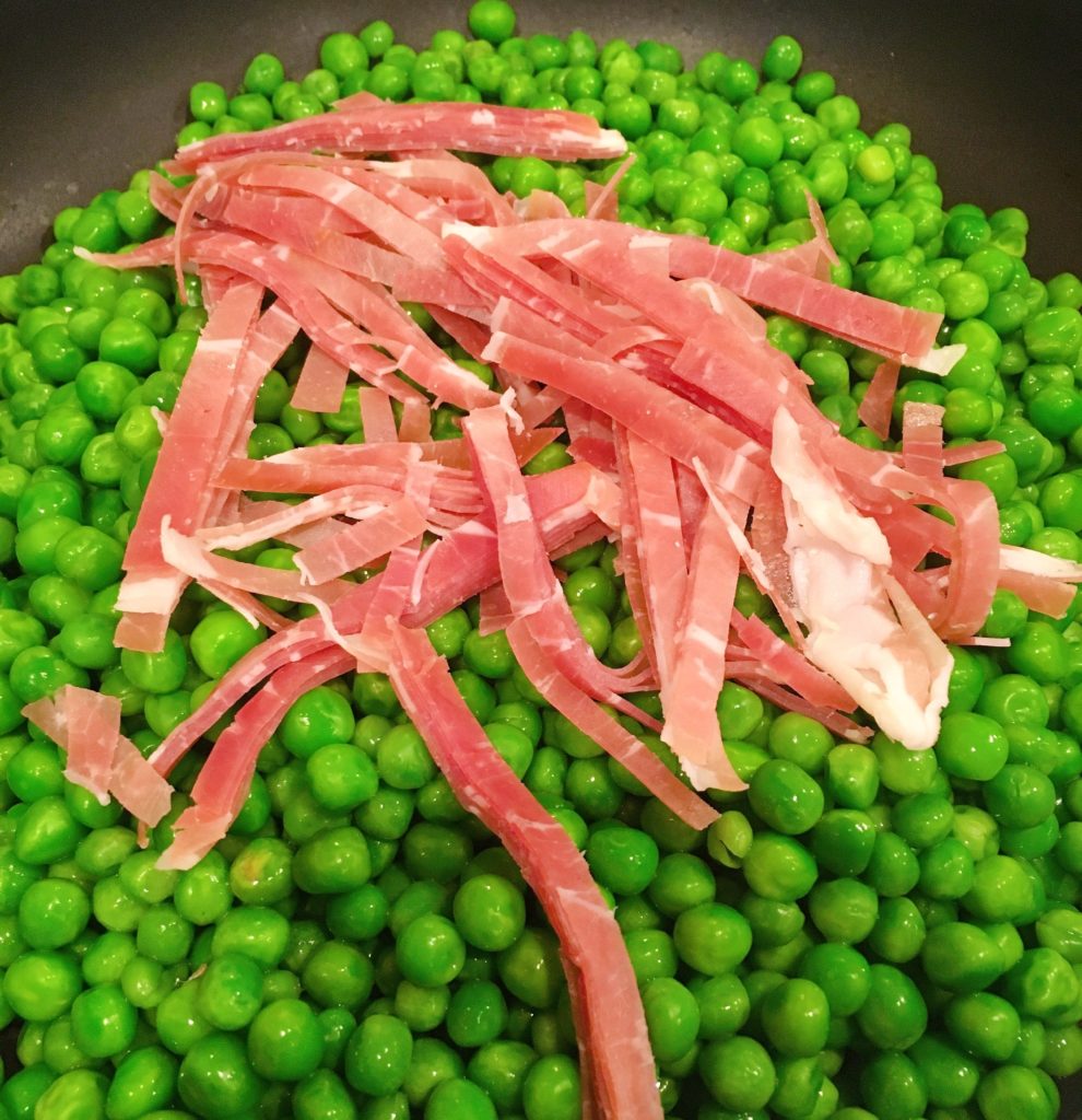 Adding Prosciutto to Peas in the skillet.