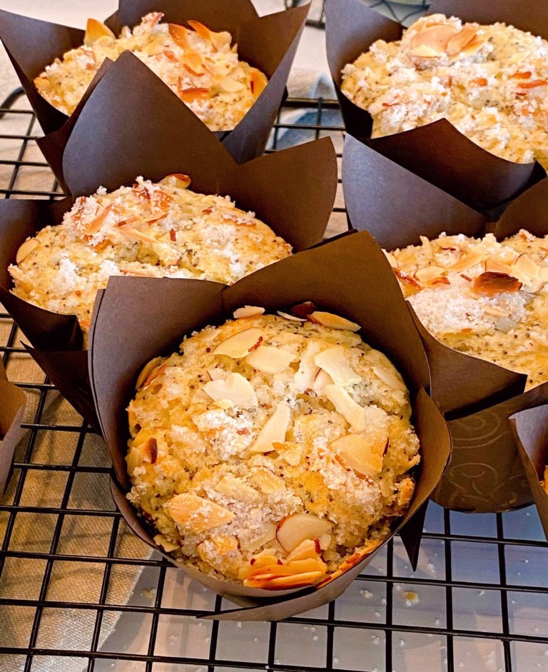 Almond Poppy Seed Muffins in brown paper liners on a cooking rack.