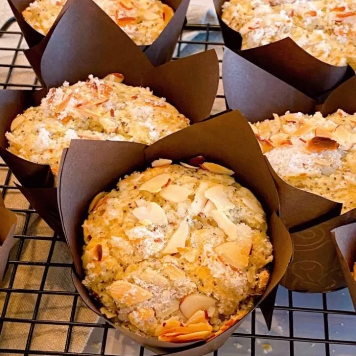Almond Poppy Seed Muffins in brown paper liners on a cooking rack.
