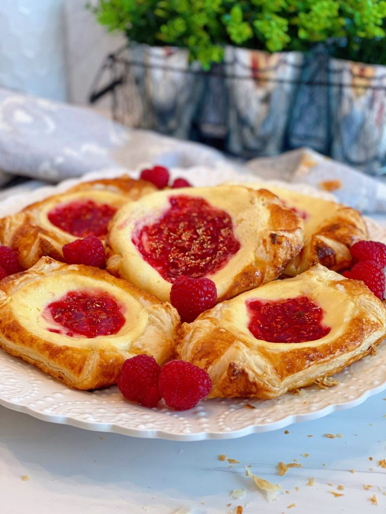 Plate full of Raspberry Cream Danishes with fresh raspberries.