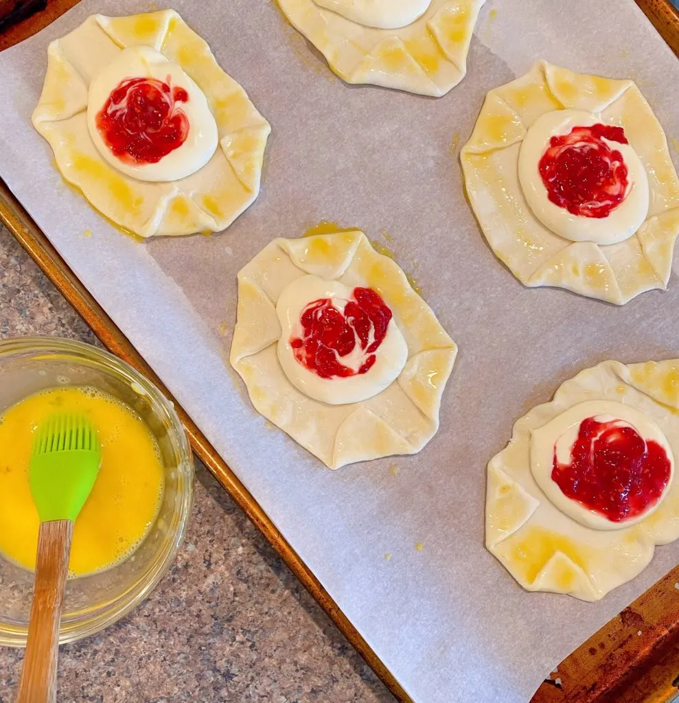 Edges of Danish being brushed with egg wash.