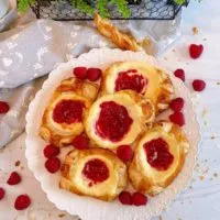 Plate full of Raspberry Cream Cheese Danish with fresh raspberries.