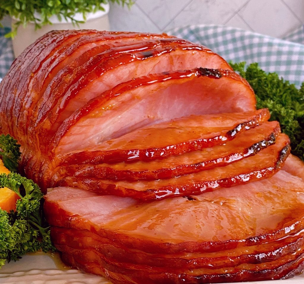 Whole Spiral Cut Home on a serving platter with Dr Pepper Glaze and garnish of parsley and orange.