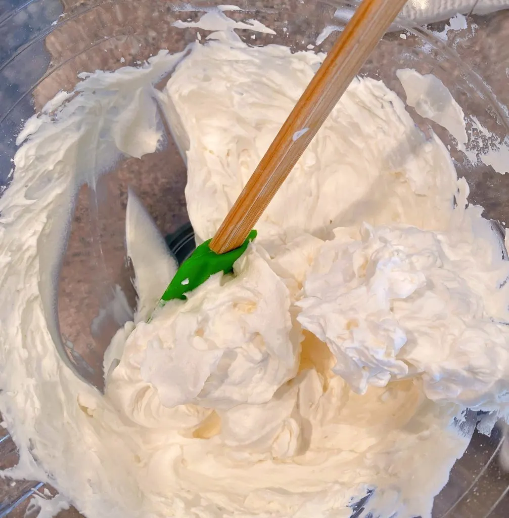 Homemade whipped cream in mixing bowl whipped to stiff peaks.