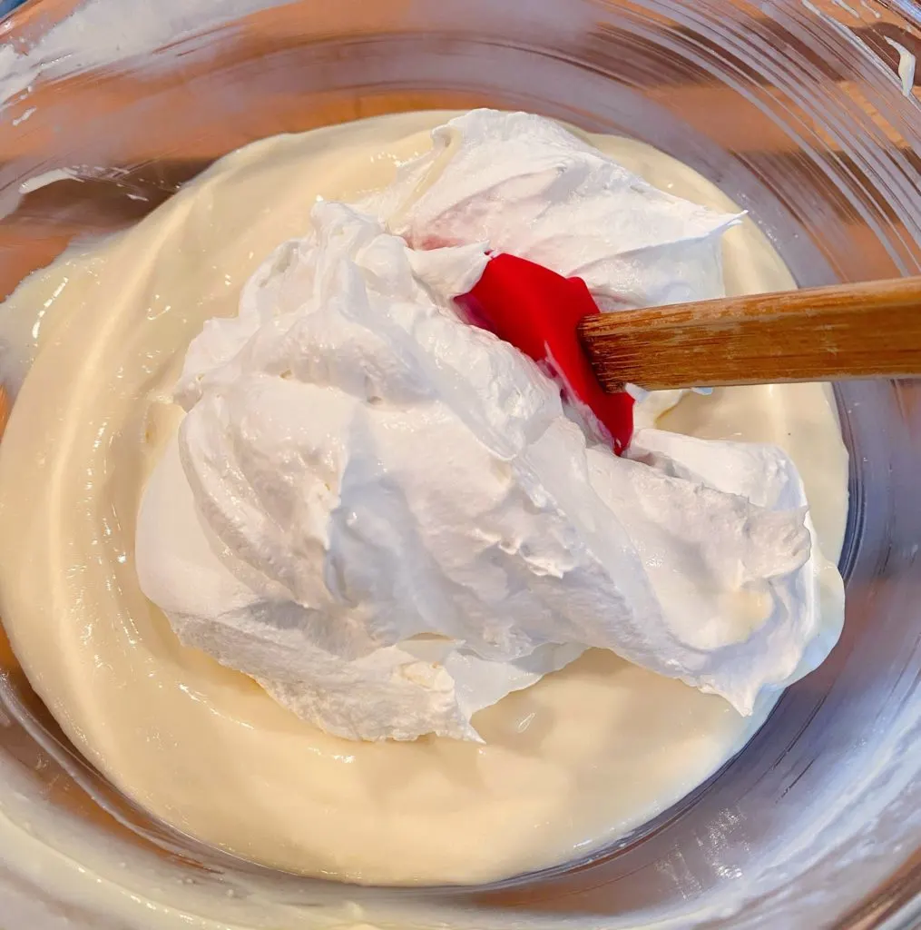 Folding Whipped Cream and cream cheese mixture together in large bowl.