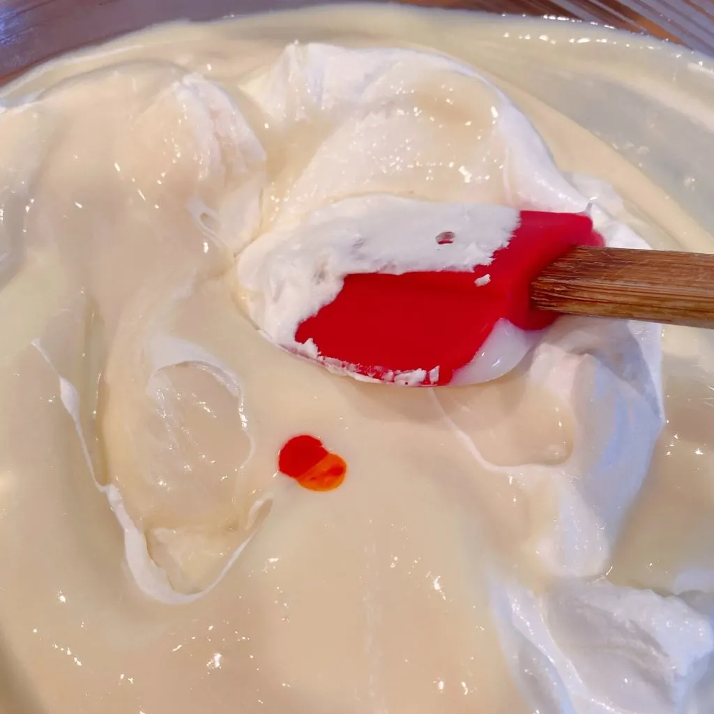 Folding whipped cream into cream filling and adding yellow food coloring. 