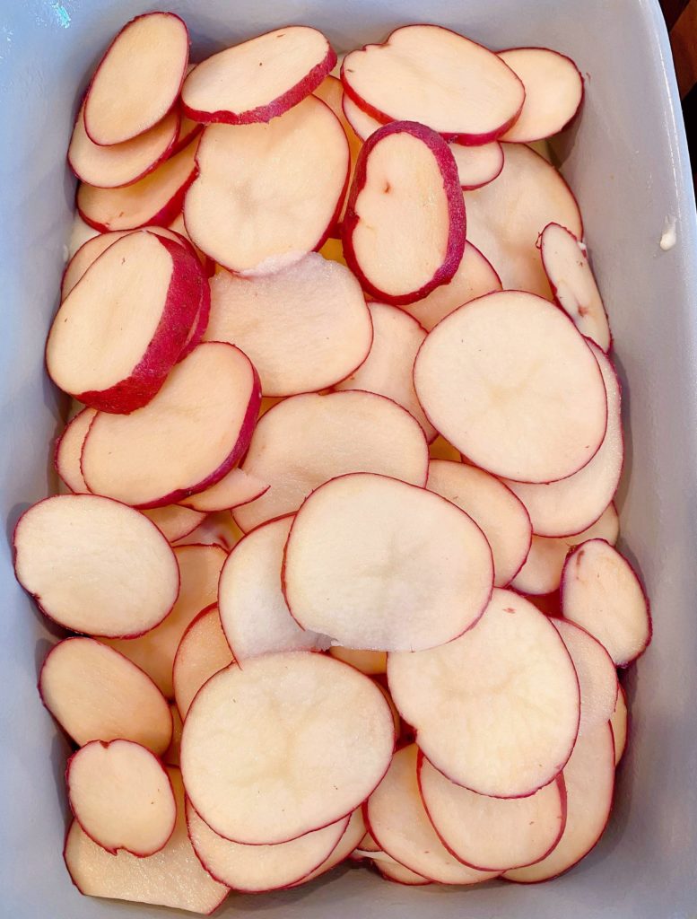 Top layer of sliced potatoes in baking dish.