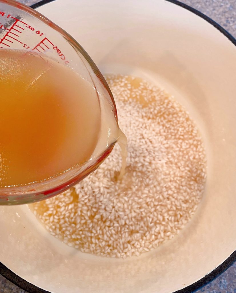 Adding chicken stock to risotto.