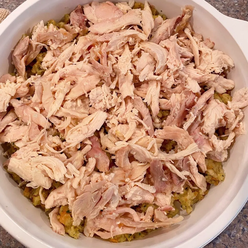 Chicken spread on top of stuffing in casserole dish.
