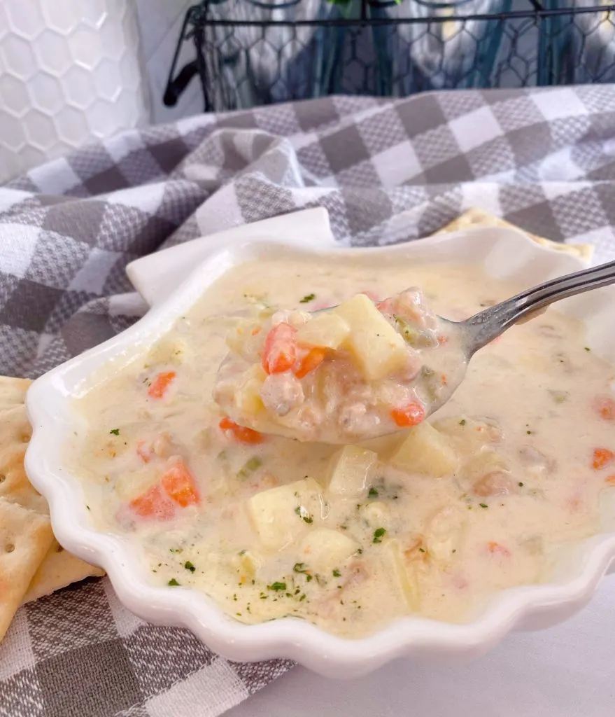 New England Clam Chowder in a clam shell bowl and a spoon full of soup.