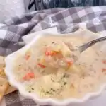 New England Clam Chowder in a clam shell bowl and a spoon full of soup.