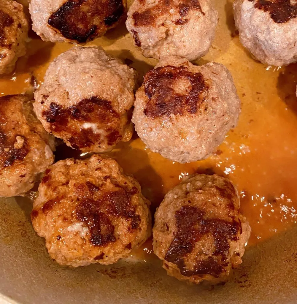 Browning meatballs in a small amount of water and in a large covered skillet.