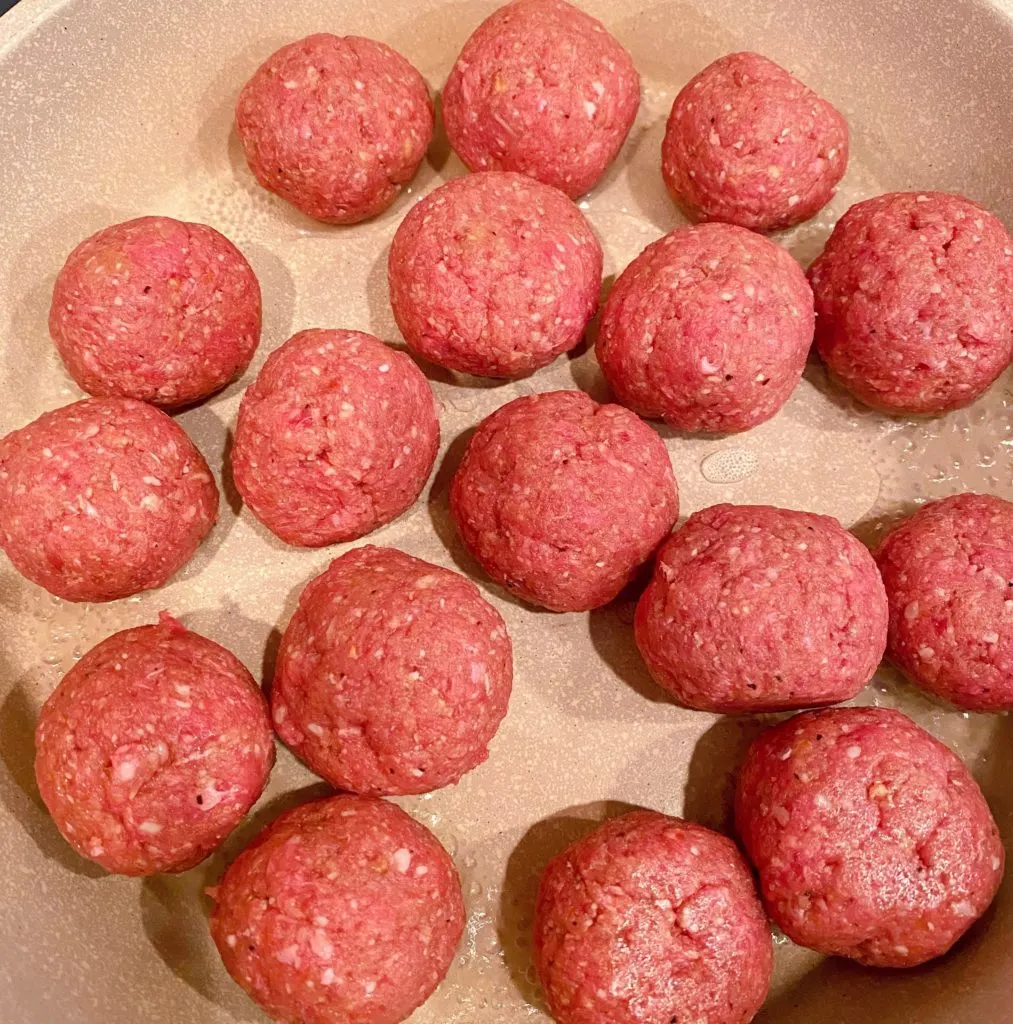 Meatballs rolled and sitting in skillet.