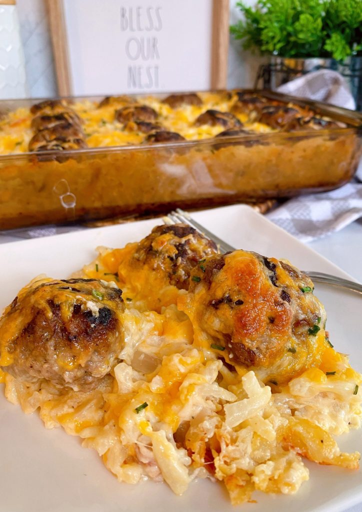 Cheesy Hash brown and Meatball Casserole in a baking dish, with a serving plate full of the casserole in front.