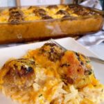Cheesy Hash brown and Meatball Casserole in a baking dish, with a serving plate full of the casserole in front.