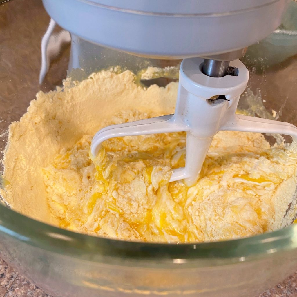 Mixing bowl of stand mixer with bread ingredients being blended.