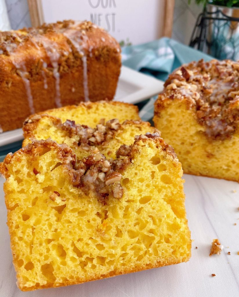 Lemon Streusel Quick Bread sliced and laying on top of each other. Larger loaf in the background.