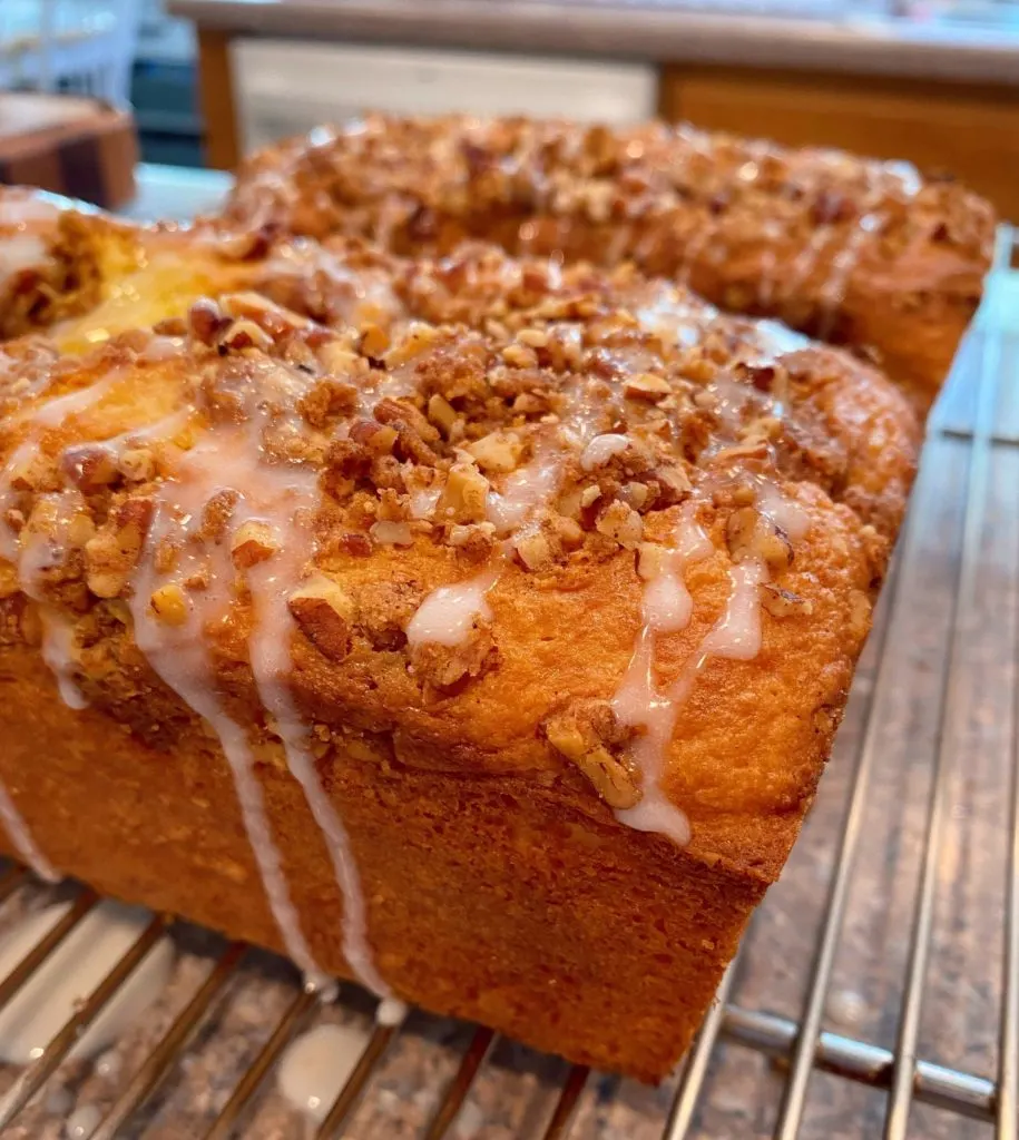 Lemon Streusel Bread on cooling baking racks with glaze drizzle.