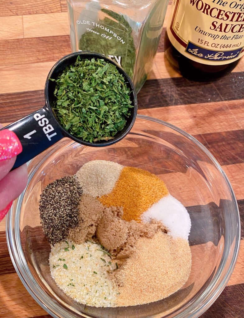 Seasonings for marinade in a small bowl adding dried parsley.
