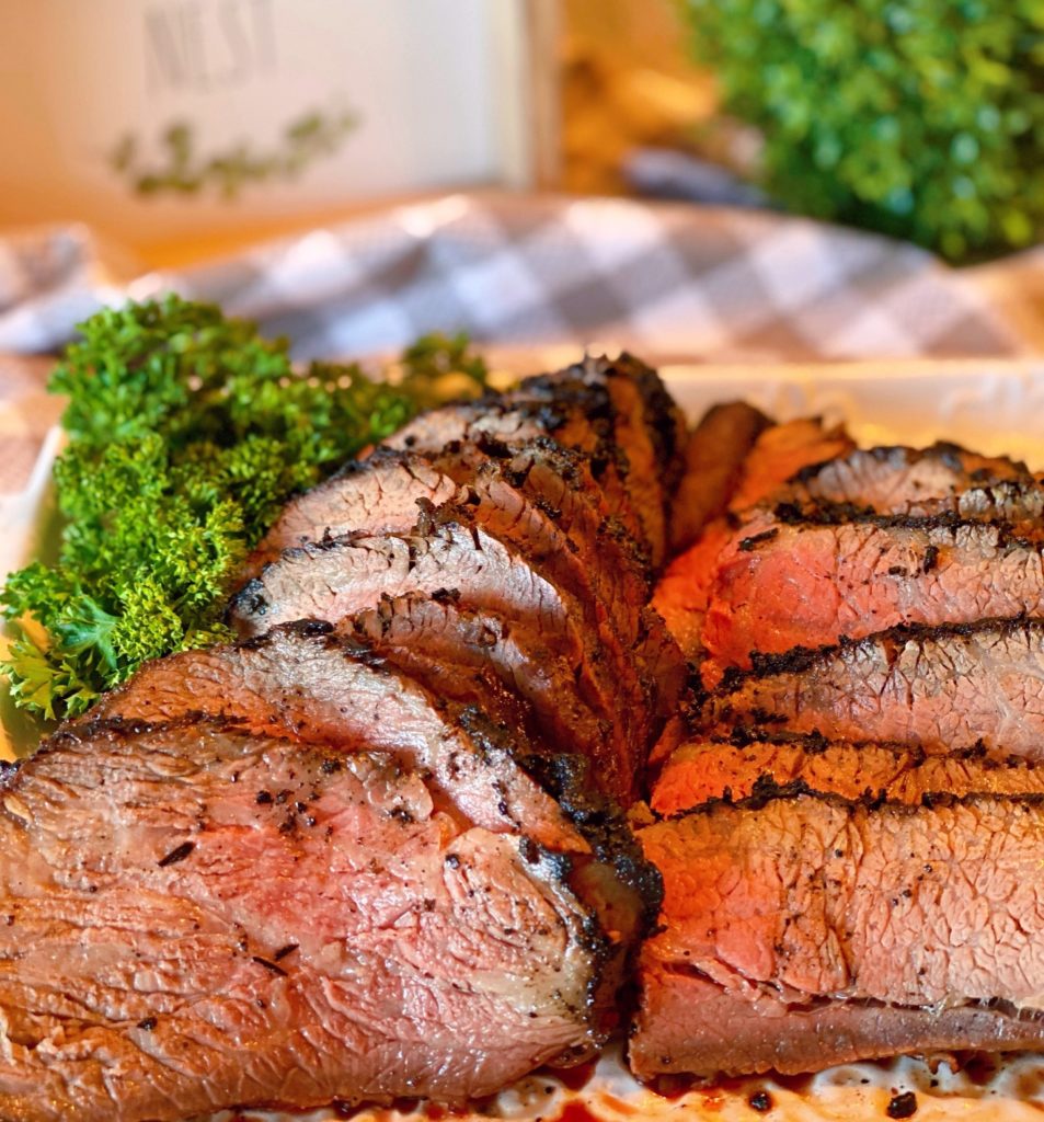 Sliced Tri-tip on a white serving platter.