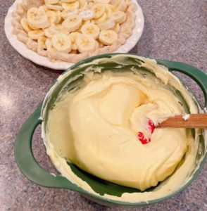 Folding whipped cream into banana pudding.
