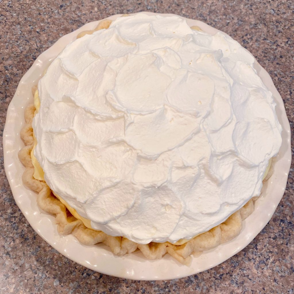 Whipping cream on top of banana cream pie.