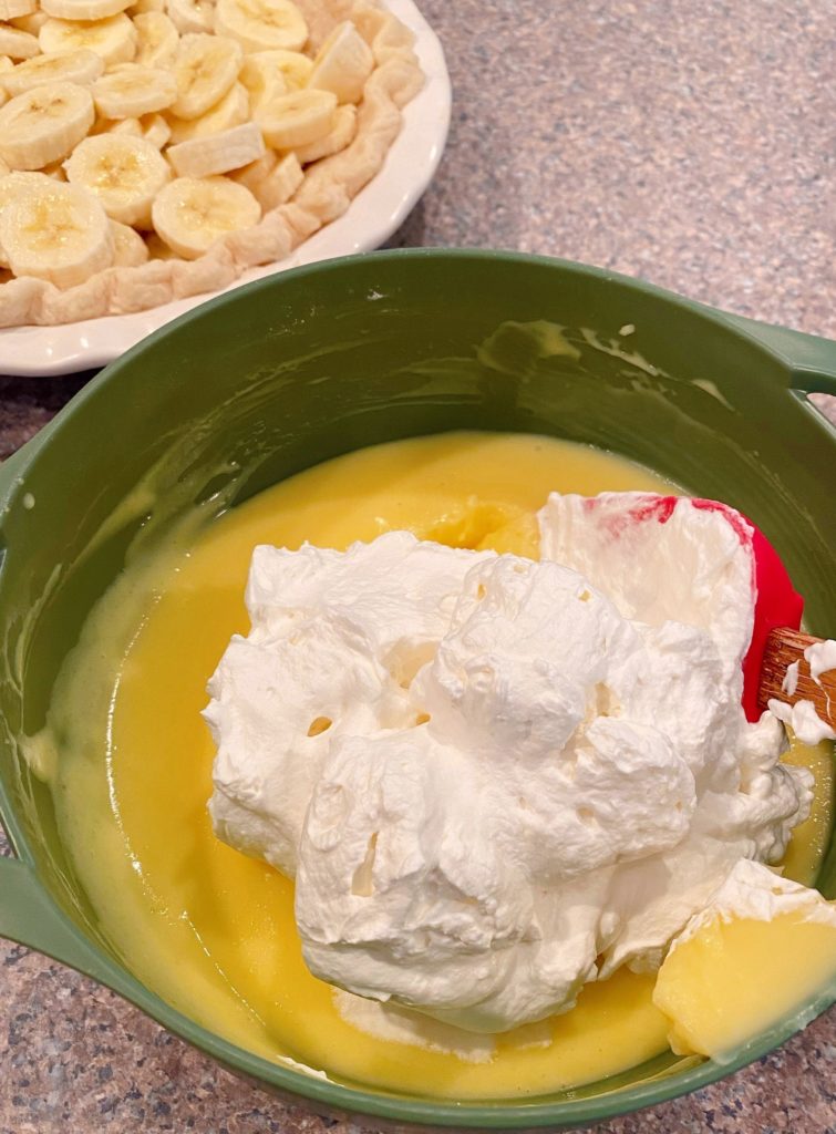 Adding whipping cream to banana cream pudding.