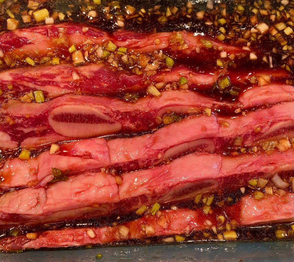 Adding beef ribs into marinade bowl.