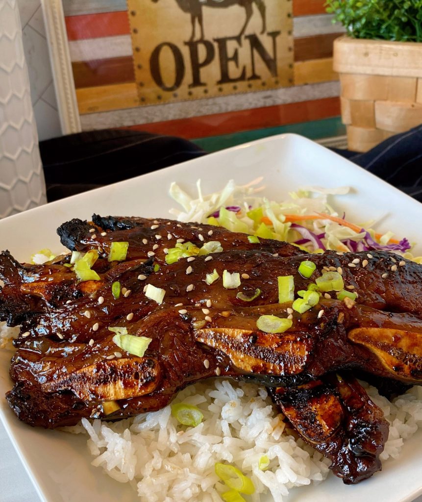 Hawaiian-Style Kalbi Grilled Beef Short Ribs on a white plate on top of white rice with cabbage.