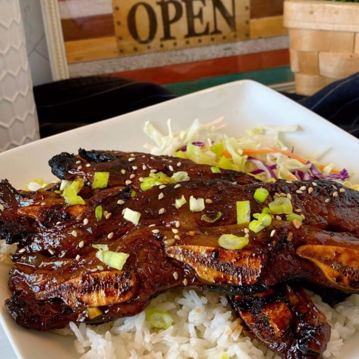 Hawaiian-Style Kalbi Grilled Beef Short Ribs on a white plate on top of white rice with cabbage.
