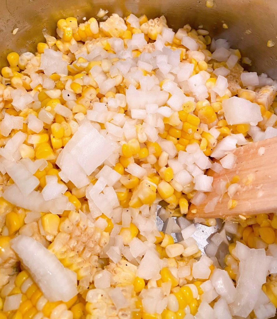 Adding chopped onion to corn and sauting in instant pot.