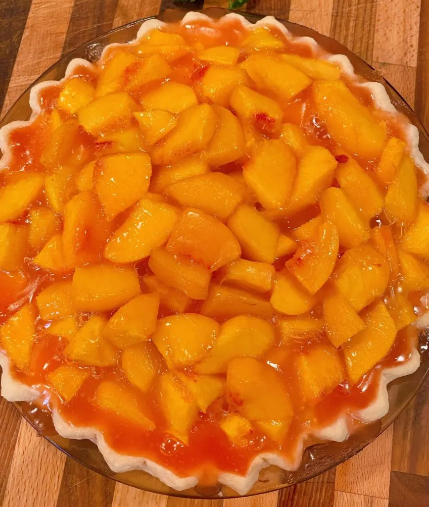 Peach Pie filling in pie crust ready to chill.