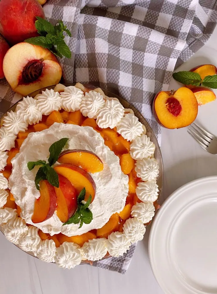 Fresh Whole Peach Pie with Whipped Cream and sliced peach garnish.