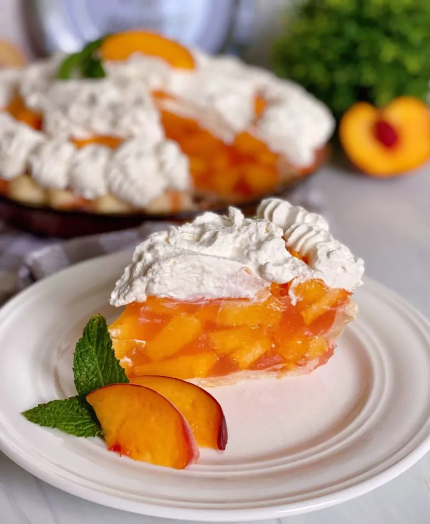 Fresh Peach Pie with a slice on a white plate with slices of fresh peaches as a garnish.