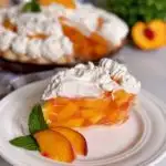 Fresh Peach Pie with a slice on a white plate with slices of fresh peaches as a garnish.