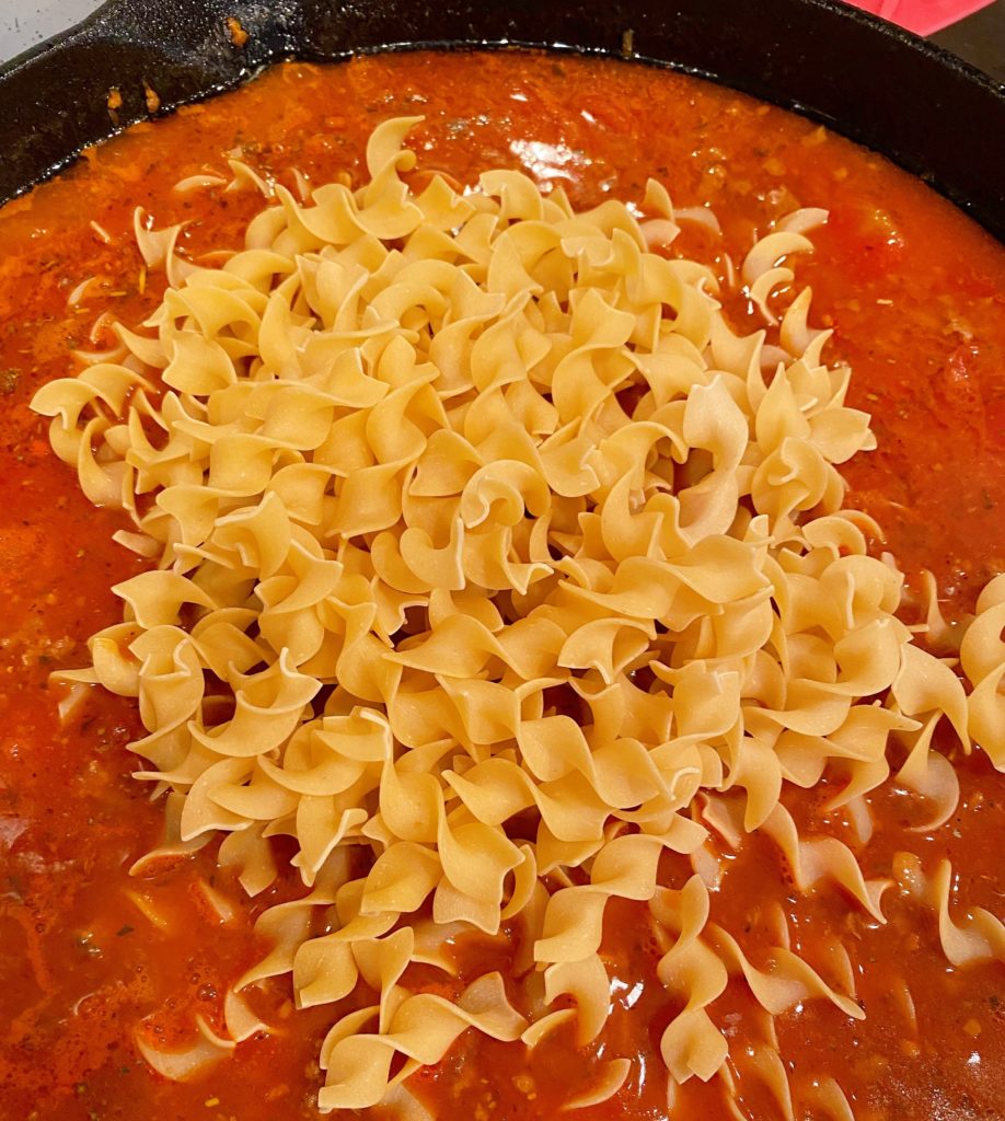 Adding egg noddles to sauce for Lasagna.