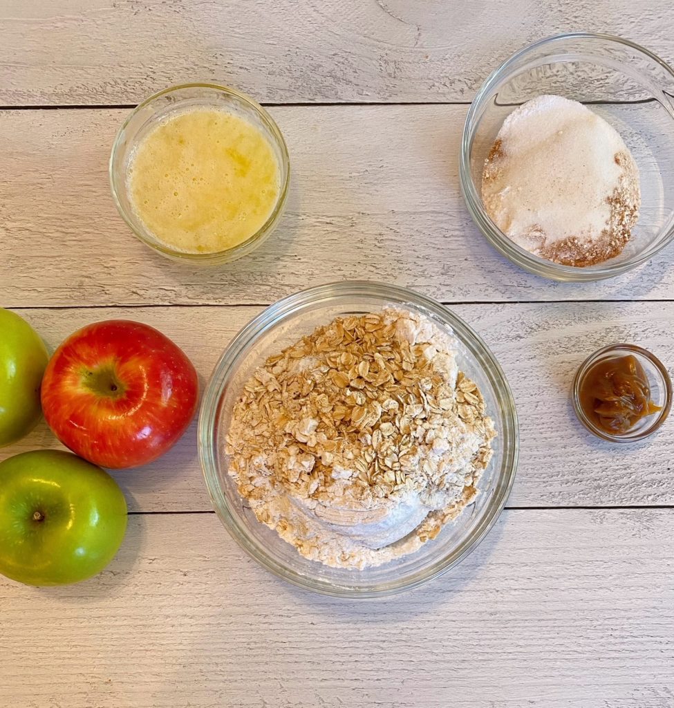 Ingredients on a white table for Caramel Apple Crisp. 